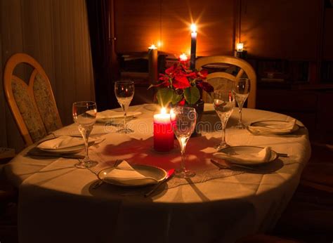 Dinner Table In Candle Light With Flowers Glasses And Plates Stock