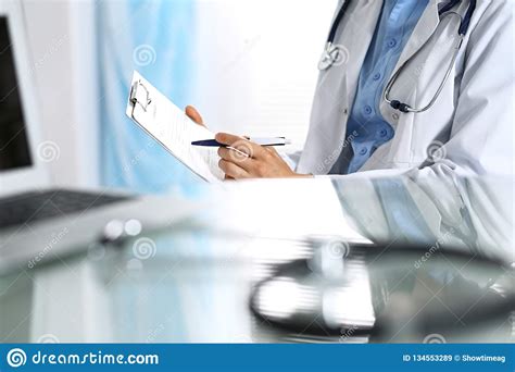 Female Doctor Filling Up Medical Form On Clipboard Closeup Reflecting