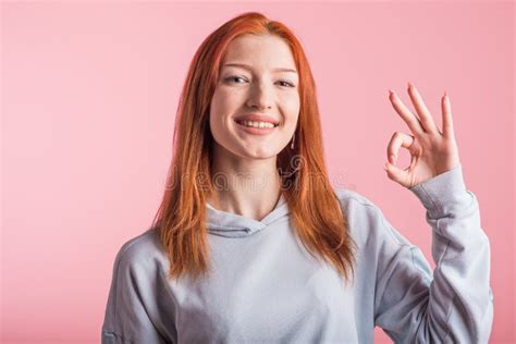 Upset Redhead Girl With Crossed Arms In The Studio On A Pink Background