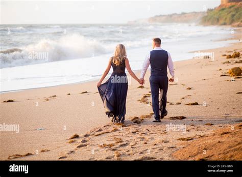 Romantic Couple Walking At The Sunset At The Sea Coats Enjoying A