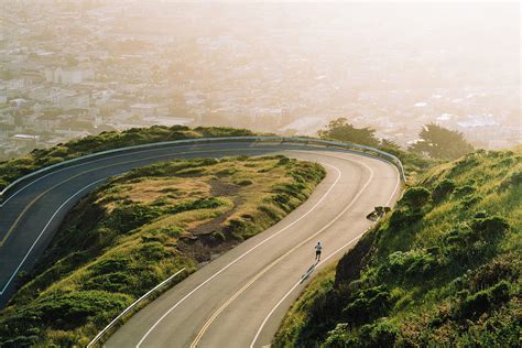 Aerial View Of Winding Road On Mountain Against Cityscape During Sunset
