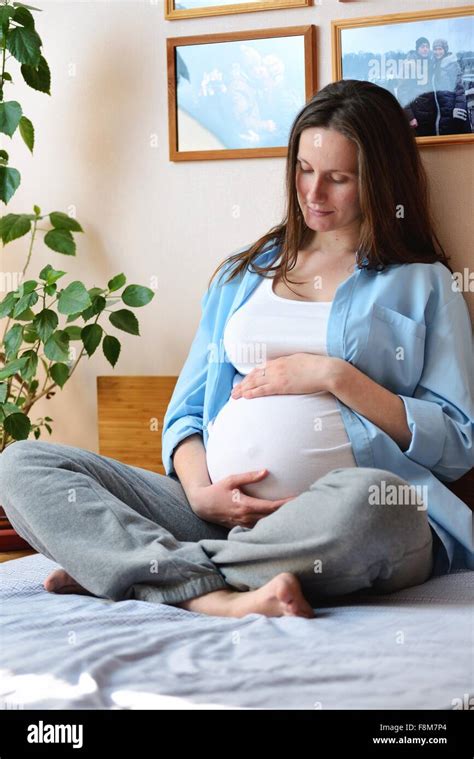 Pregnant Woman Sitting On Bed Holding Stomach Stock Photo Alamy