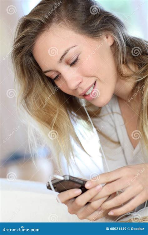 Cheerful Young Woman Using Mobile Phone And Earphones Stock Image