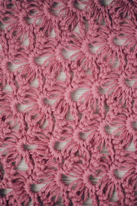 A Close Up View Of A Pink Crochet Pattern On A Table Cloth With White