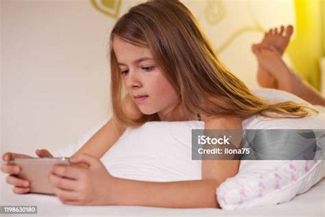 junges mädchen mit ihrem smartphone im bett liegend flache tiefe stockfoto und mehr bilder von