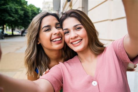 Free Photo Portrait Of Two Young Friends Taking A Selfie While Standing Outdoors On The Street