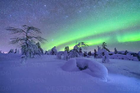 Northern Lights Over Snow Covered Landscape At Dusk Stock Photo