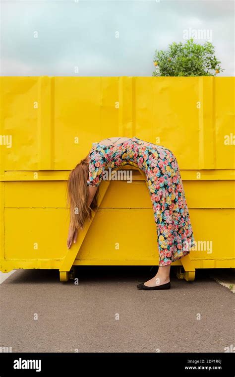 Woman In Flower Dress Bending Over Attachment Of Yellow Container Stock Photo Alamy