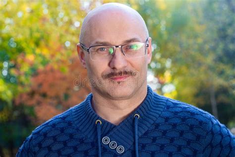 Portrait Of An Intelligent Bald Man With Glasses In A Park Stock Photo