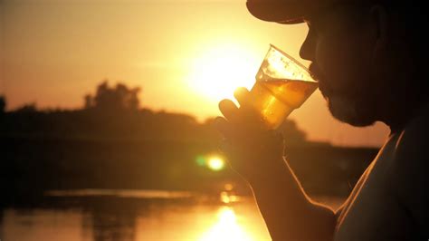 Close Up Shot Of A Young Caucasian Man Drinking Beer Outside At Sunset