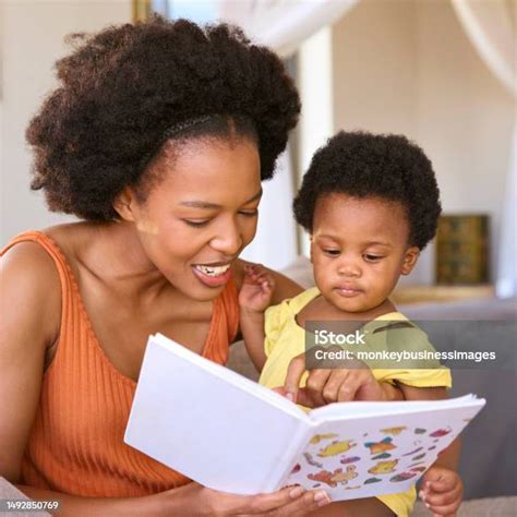 Ibu Duduk Di Sofa Di Rumah Dengan Putri Muda Membaca Buku Bersama Foto