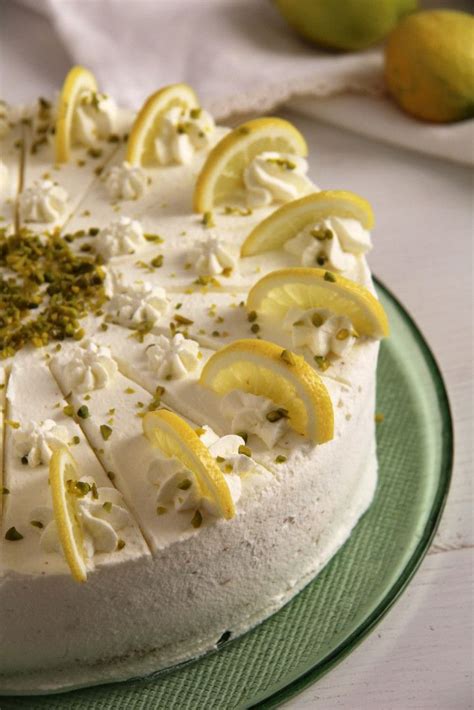 A White Cake With Lemons And Herbs On It Sitting On A Green Platter