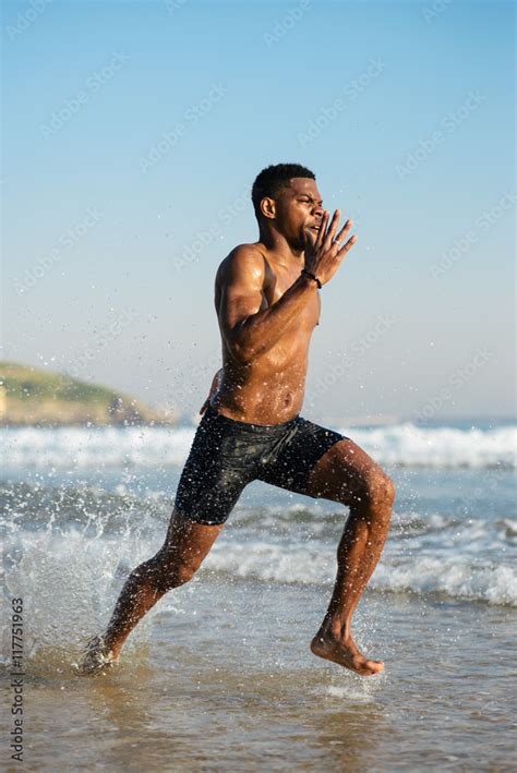 Fit Black Man Running By The Sea Splashing Watter Black Runner