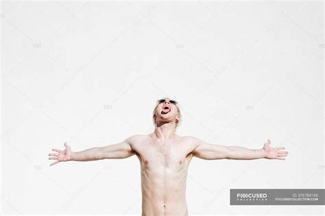 Shirtless Young Man With Arms Outstretched And Mouth Open Standing Against White Wall — 20 30