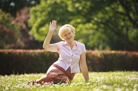 Maturity European White Hair Woman Sitting On Grass And Having Fun