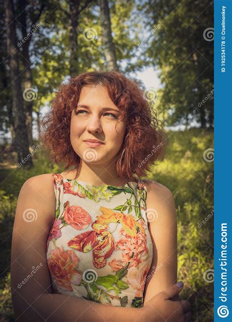 Red Haired Curly Haired Girl In A Summer Dress Posing In The Village