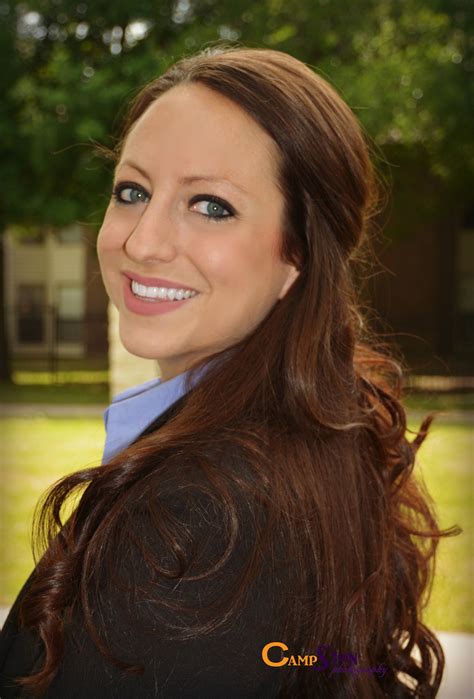 A Woman With Long Brown Hair And Blue Eyes Smiles At The Camera While