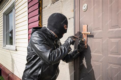 Premium Photo Man In A Black Balaclava Mask Opens A Locked Door With