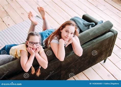 Two Cute Smiling Girls Children Friends Tweens Sitting On Sofa At Home