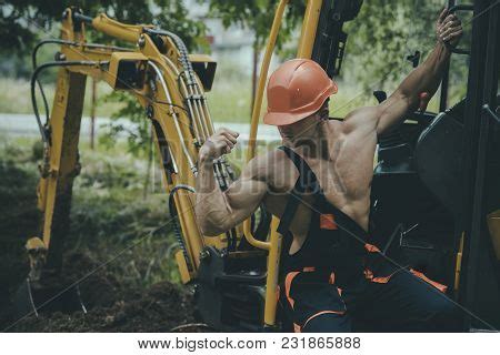 Sexy Man With Nude Torso Near Construction Equipment Or Excavator On