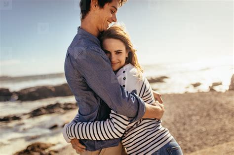 Happy Couple Hugging Each Other Standing At The Beach Stock Photo