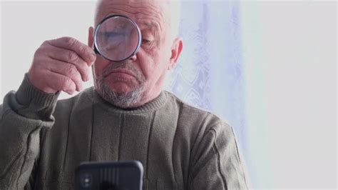 Old Grandpa Uses A Magnifying Glass To Read From His Smartphone By Berdiy88
