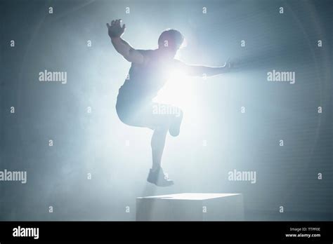 Adaptive Athlete With Arms Outstretched Jumping On Box In Gym Stock