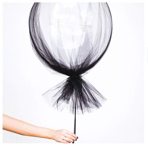 A Woman Holding A Balloon With Black Tulle