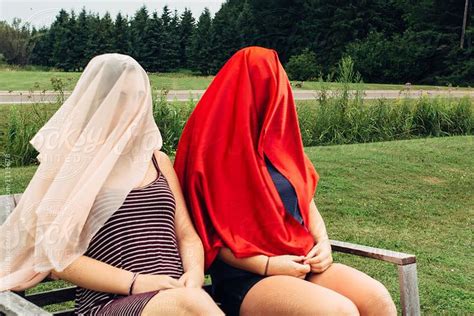 view two teenage girls sitting on a bench with heads covered by stocksy contributor gabriel