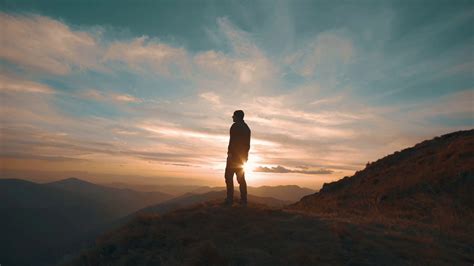 The Man Standing On The Mountain Against The Beautiful Sunset Stock