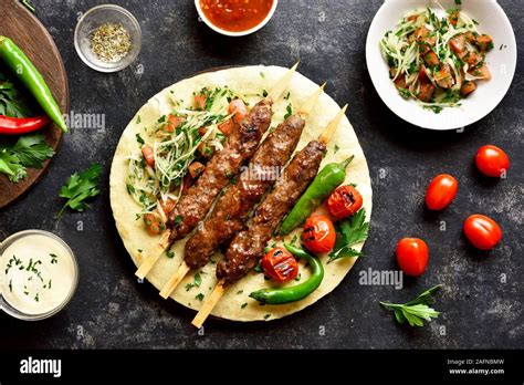 Turkish Adana Kebab With Fresh Vegetables On Flatbread Over Black Stone