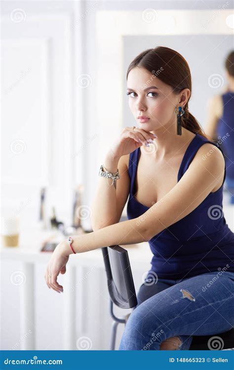 Young Woman Sitting On A Chair Isolated Over White Background Stock