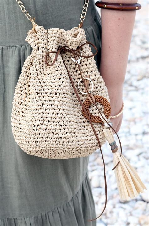 A Woman Is Holding A Crocheted Bag With Tassels On The Handles