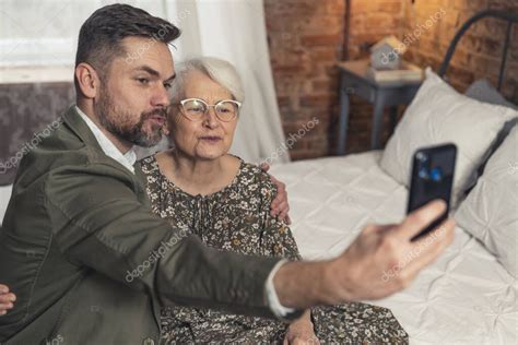 Abuela De Pelo Corto Y Su Nieto Barbudo Haciendo Cara De Pato Y Tomando Una Selfie Durante El