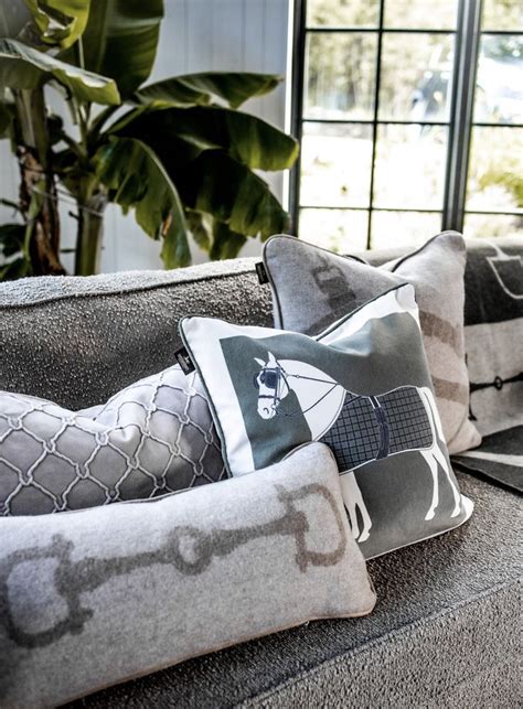 Pillows On A Couch In Front Of A Large Window With Potted Plants Behind It