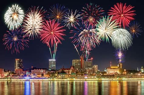 Fireworks Are Lit Up In The Night Sky Over Water And Cityscape With