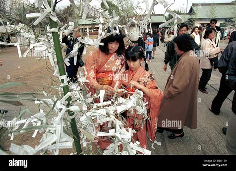 Two Young Girls In Traditional Kimonos Read Omikuji Kind Of Goodwill Tags Which Forecast Their