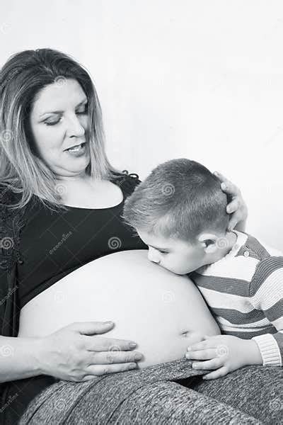 eight month pregnant woman and three year old son kissing belly stock image image of people