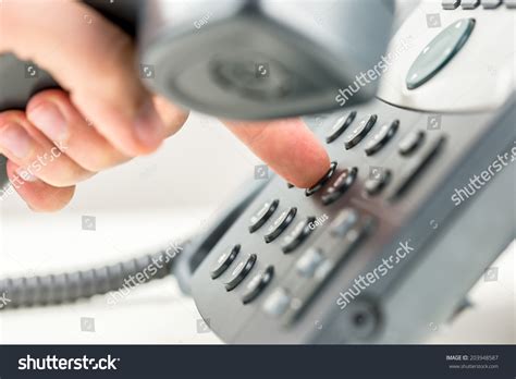 Man Dialing Out On A Telephone Holding The Receiver In His Hand And