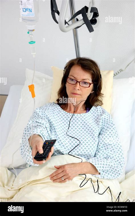 patient lying in a hospital bed operating the tv with a remote control listening to the sounds