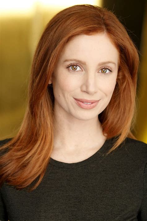 A Woman With Red Hair Is Smiling At The Camera
