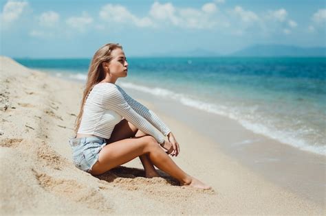 Menina Loura Que Senta Se Na Areia Na Praia Foto Premium