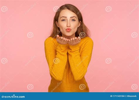 portrait of gorgeous ginger girl in sweater sending sensual air kiss from open palms looking