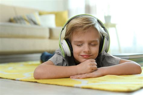 Cute Little Boy With Headphones Listening To Audiobook At Home Stock