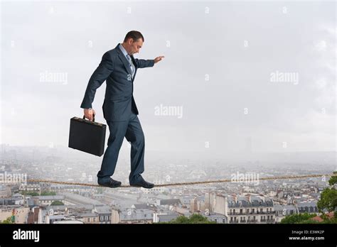 businessman walking across a highwire or tightrope balancing above the