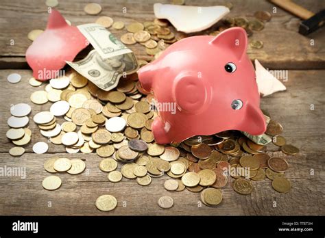 Broken Piggy Bank With Cash And Coins On Wooden Background Stock Photo