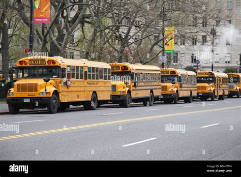 A Line Of American Yellow School Buses Wait For Students Outside The