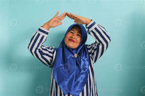 An Excited Middle Aged Asian Woman In A Blue Hijab And Striped Shirt Is