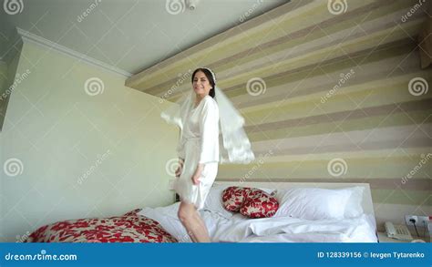 jeune jeune mariée heureuse dans un déshabillé sautant sur le lit banque de vidéos vidéo du