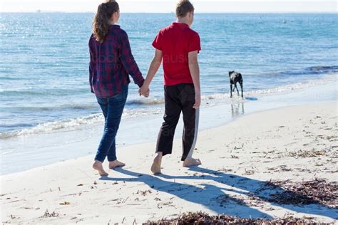 Image Of Young Couple Walking Along Beach Holding Hands Austockphoto